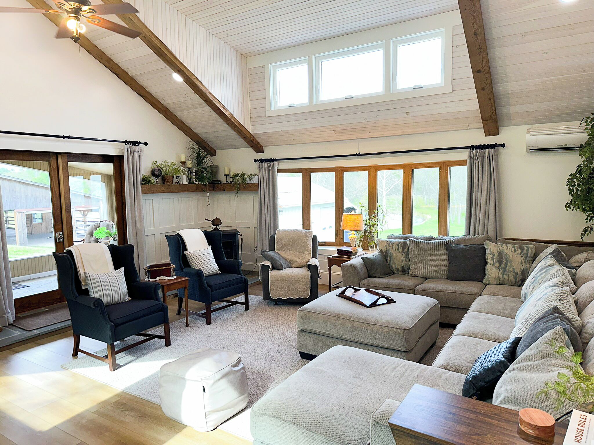 Un salon spacieux avec un haut plafond, de grandes fenêtres et un coin salon confortable.