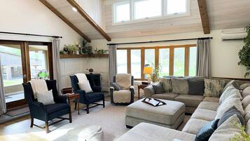 Un salon spacieux avec un haut plafond, de grandes fenêtres et un coin salon confortable.