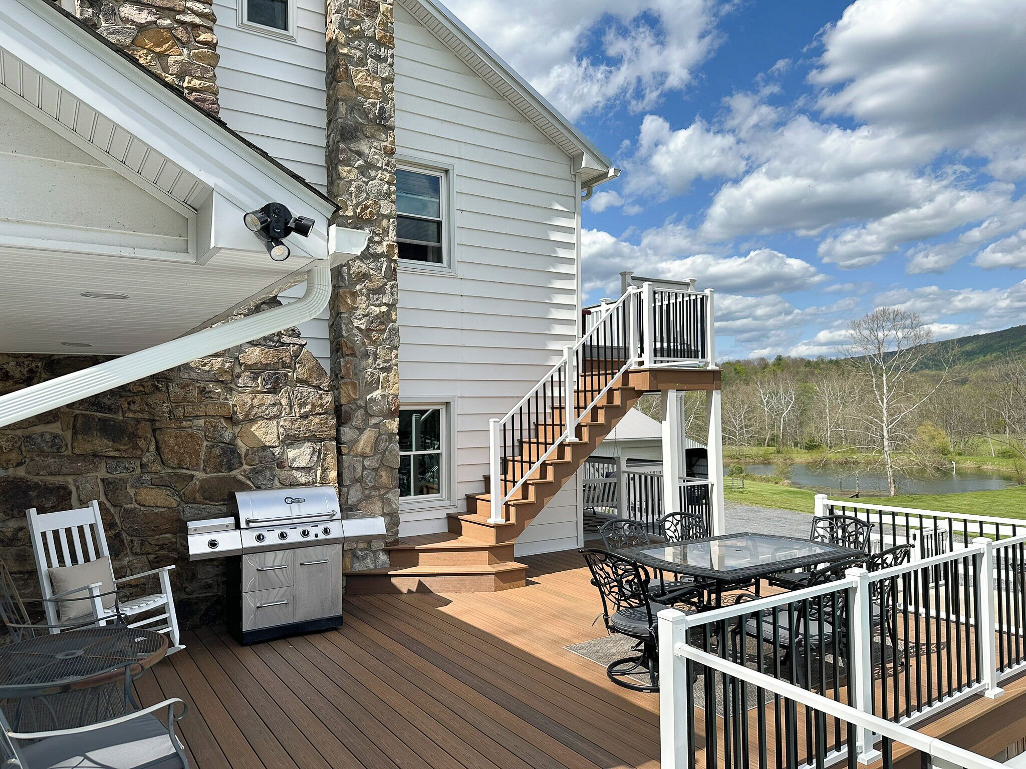 Une terrasse aménagée avec du mobilier d’extérieur, un barbecue et un escalier menant à une autre terrasse.