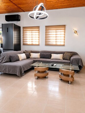 Ein modernes Wohnzimmer mit einer Eckcouch, einem Glastisch und einer außergewöhnlichen Leuchte.