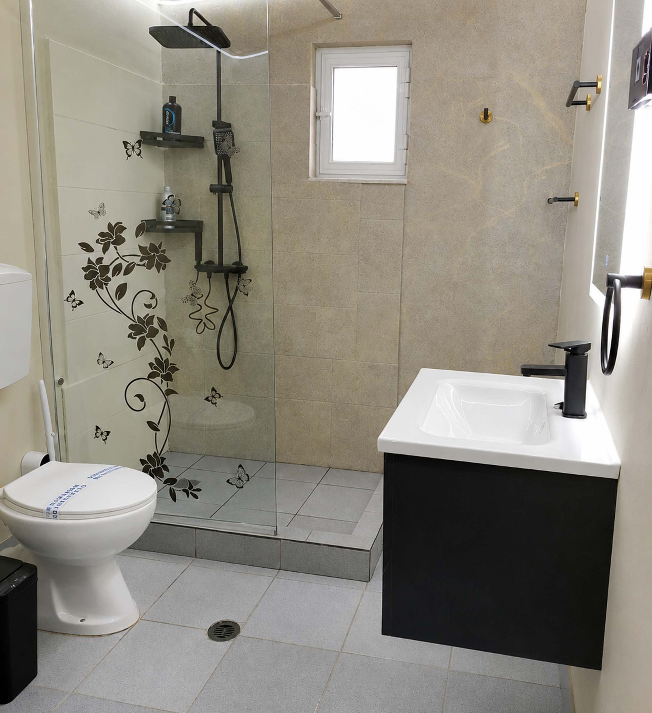 A bathroom with a toilet, a shower, a sink, and a window.