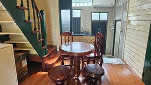 Ein Essbereich mit Holztisch und -stühlen, eine Treppe mit grünen Geländern und einer dekorativen Deckenleuchte.