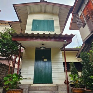 Un edificio de dos pisos con una puerta verde y un pequeño porche.
