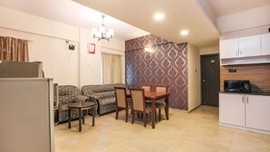 A compact living space with a dining area, kitchen, and a patterned wall. - Frazer Suites (Bengaluru)