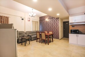 A compact living space with a dining area, kitchen, and a patterned wall. - Frazer Suites (Bengaluru)