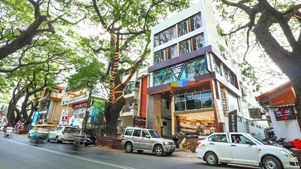 A multi-story building with commercial spaces on the ground floor, including a cafe and a shop with a sign that reads 'Classic Steps.' - Frazer Suites (Bengaluru)