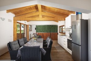 Eine moderne Küche mit Holzbalkendecke, einem Essbereich mit Korbmöbeln und einer grünen Wand.