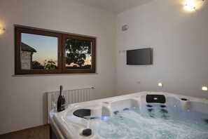 Ein Zimmer mit Whirlpool, einem Fenster mit Blick und einem Wand-Fernseher, sowie einer Champagnerflasche.