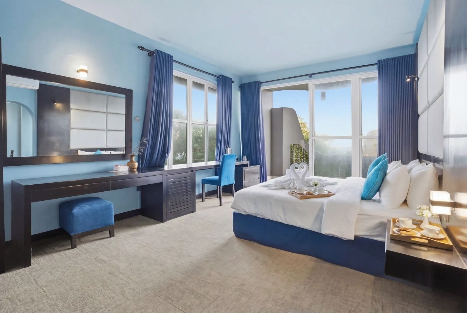 Une chambre d’hôtel moderne avec un grand lit, un bureau, une chaise et une grande fenêtre avec des rideaux.
