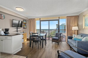 Ein Hotelzimmer mit Balkon, Essbereich, Wohnbereich und Fernseher an der Wand.