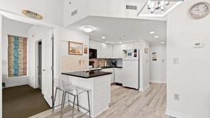A modern kitchen with white cabinetry, a central island, and a dining area with bar stools. - HS-0111 Ocean Front | Pool | Hot Tub | Lazy River (Myrtle Beach)