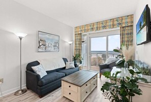 Ein Wohnzimmer mit Sofa, Couchtisch und Meerblick vom Balkon.