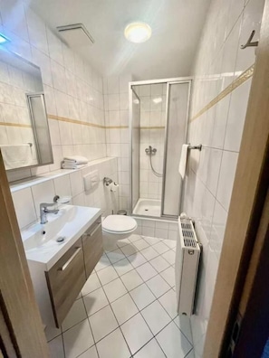 Un bany amb vàter, rentatge, mirall i plat de dutxa.