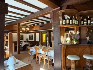 A rustic interior with wooden beams, a bar area with wine bottles, and a dining space with chairs and tables. - Ilcastello-Walderholung (Hohndorf)