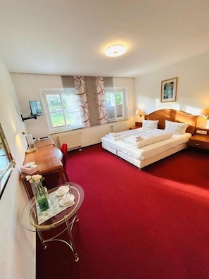 A hotel room with a bed, a table with a vase, and a window with blinds. - Ilcastello-Walderholung (Hohndorf)
