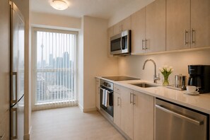 Eine moderne Küche mit Edelstahlgeräten, einem großen Fenster mit Jalousien und Blick auf die Stadt.
