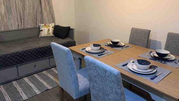 Een eethoek met een tafel voor vier personen, een bank en een schilderij aan de muur.
