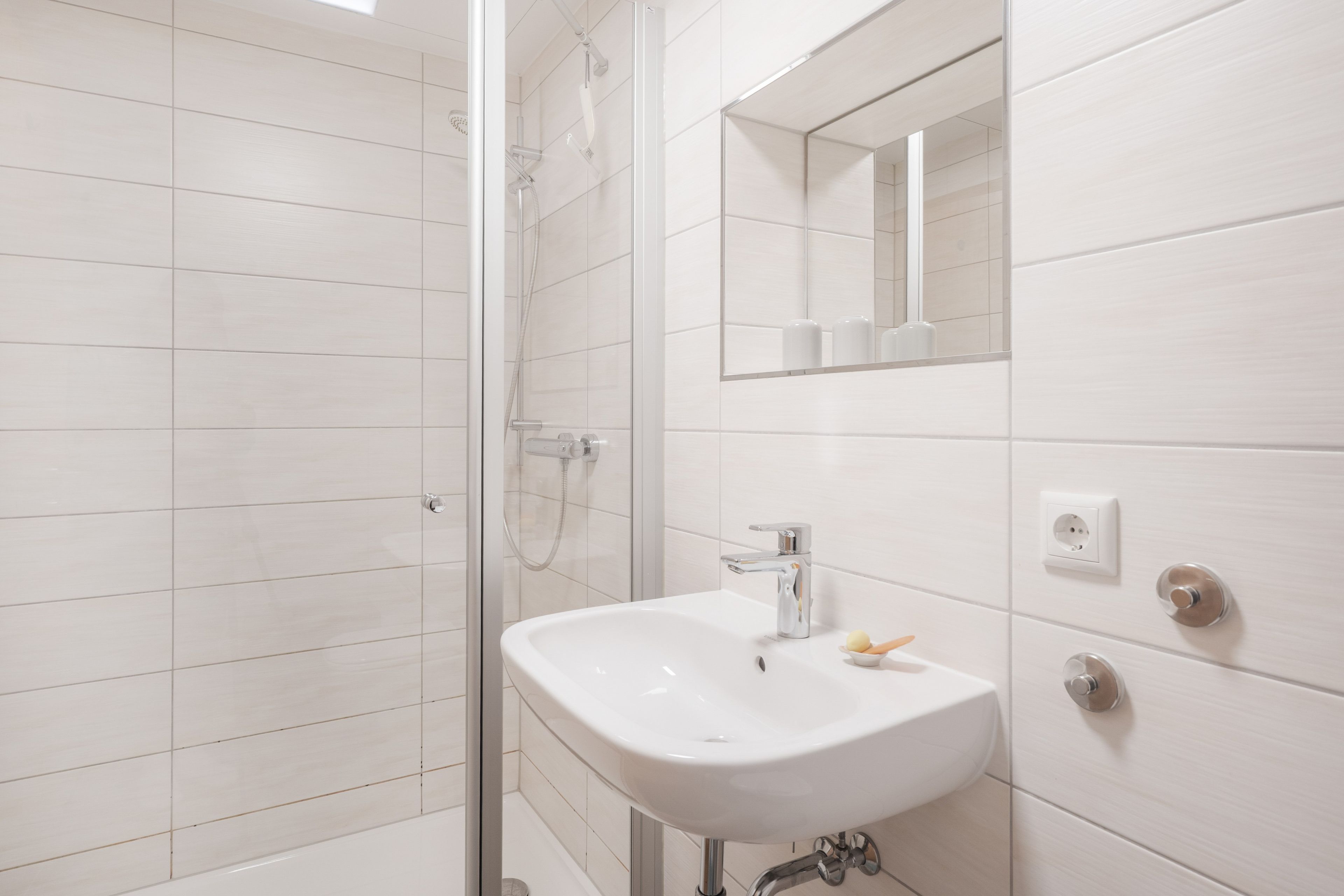 Ein modernes Badezimmer mit einer Duschkabine aus Glas, einem weißen Waschbecken mit Spiegel darüber und einer Toilette mit Bidetfunktion.