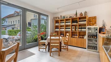 Ein Restaurantinneres mit Essbereich, Holzregalen mit Flaschen und Blick durch große Glastüren.