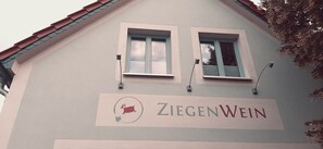 A building with two windows and a sign that reads 'Ziegenwein'.