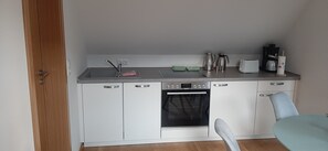 A compact kitchen with a sink, stove, and coffee maker.