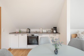 A modern kitchenette with a built-in oven, a coffee maker, and a toaster. - Apartment 'Ziegfried#Ziegenhof' (Radebeul)