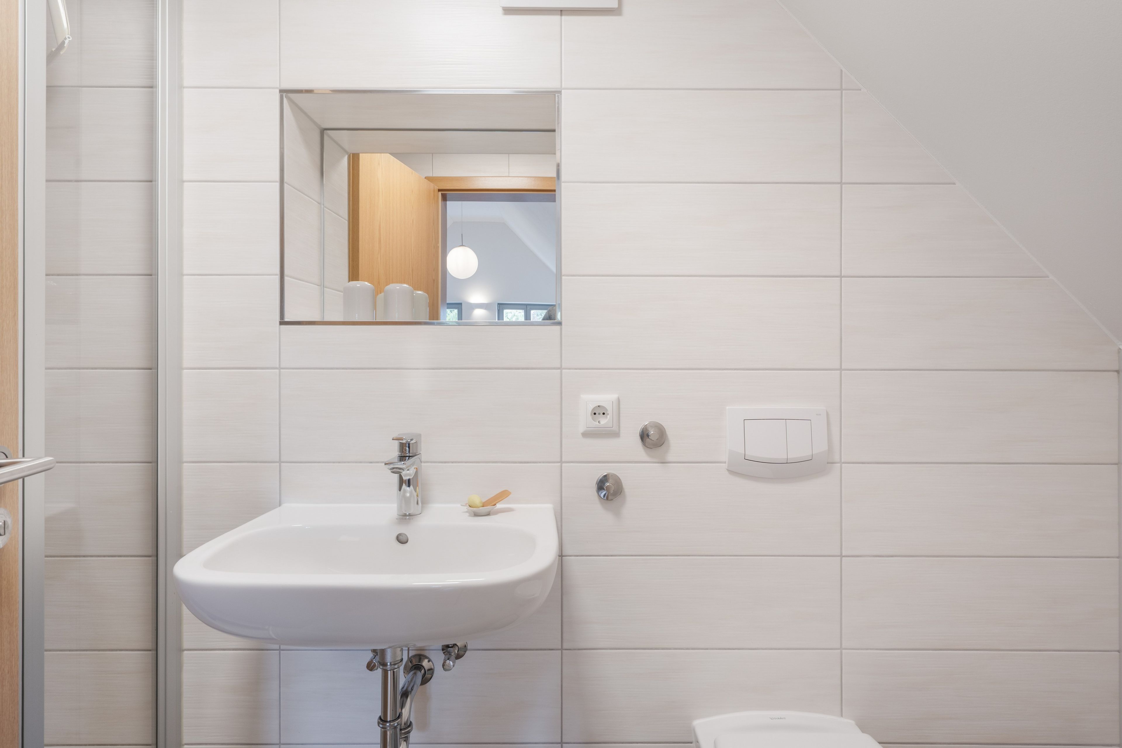 Ein Badezimmer mit einem weißen Waschbecken, einem Spiegel und einer Toilette.