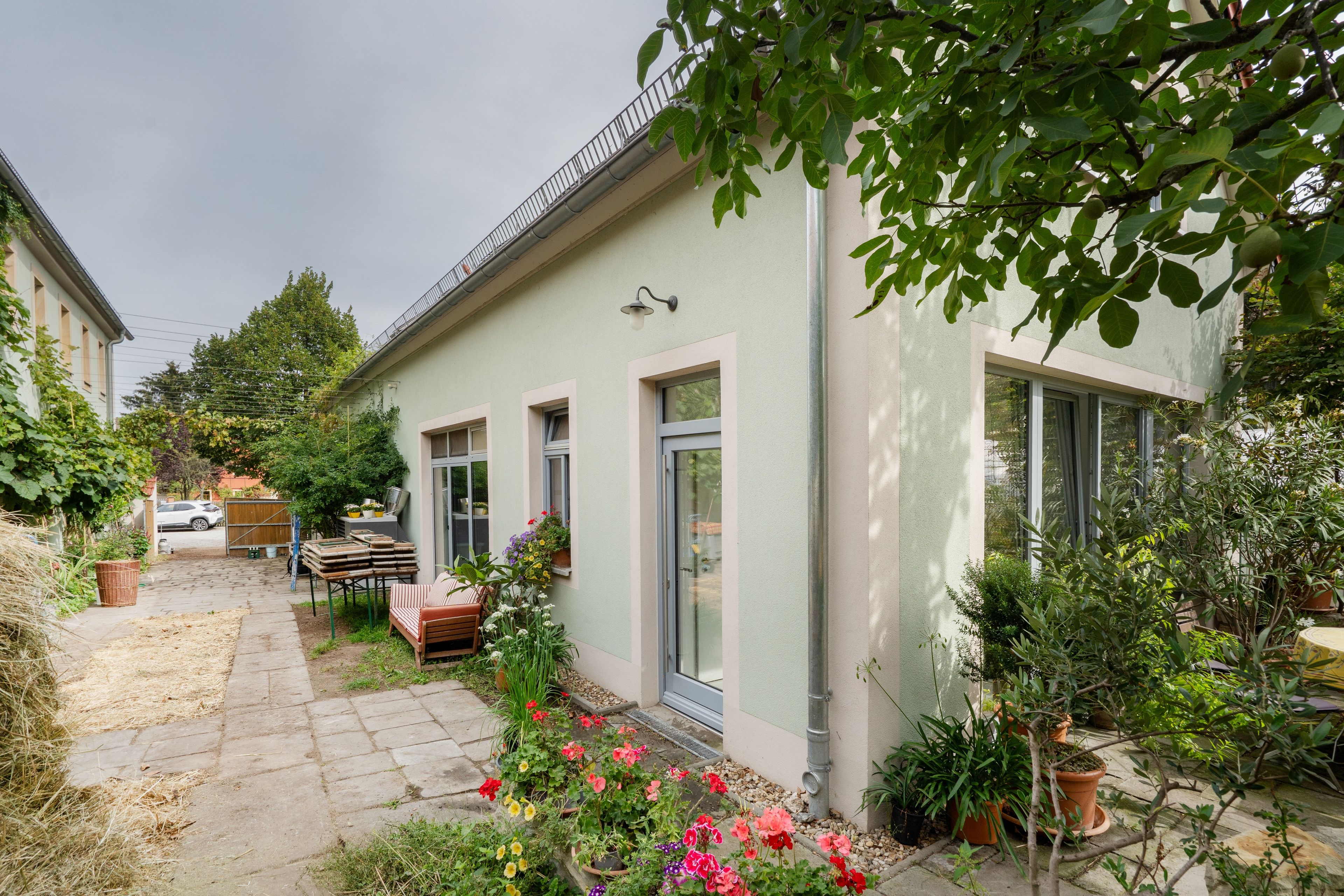 Un immeuble résidentiel doté d’une terrasse dallée, d’une table en bois et de plantes en pot.