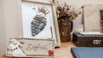 A framed artwork of a bunch of grapes, a decorative item with a name, and a vase with dried flowers.