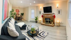 Ein Wohnzimmer mit einer Couch, einem Couchtisch, einem Kamin und einem Essbereich im Hintergrund.