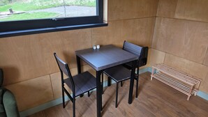 Una habitación pequeña con una mesa, dos sillas, un ventanal y un radiador.