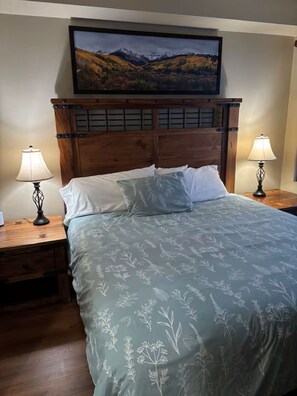A bedroom with a bed, two bedside lamps, a wooden headboard, and a framed landscape picture on the wall. - Perfect Peace by the Lake (Keystone)