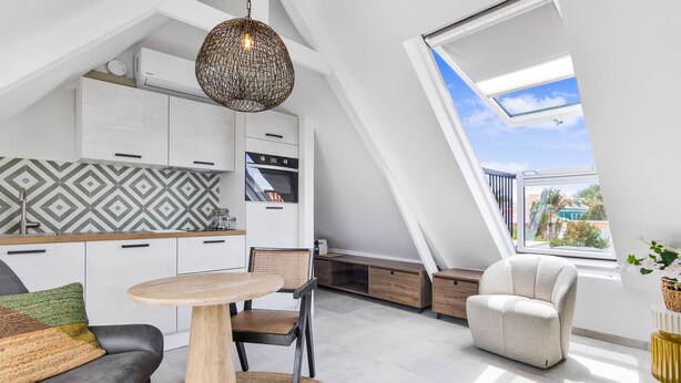 Un apartament modern d'estil loft amb cuina, zona de menjador i una finestra gran que ofereix una vista.