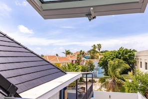 Ein Balkon mit Blick auf farbenfrohe Häuser, eine Palme und einen klaren Himmel.