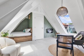Ein Schlafzimmer im Loft-Stil mit einem Bett, einem Sessel, einem Tisch und einer Hängeleuchte.