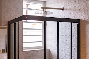 Eine Eckdusche mit strukturierter Wand und Fenster.