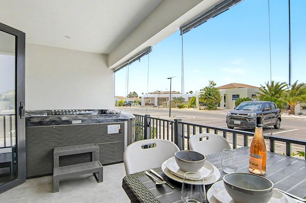 A balcony with a hot tub, outdoor seating, and a view of a street with cars and buildings. - Mambo Stay,  luxury apartment with Hot Tub (Willemstad)