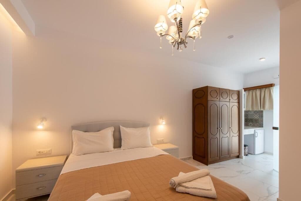 A bedroom with a bed, nightstands, a wardrobe, and a bathroom visible in the background.