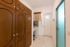A hallway with wooden cabinets, a white door, and a tiled floor.