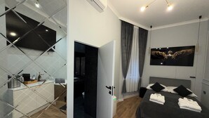 A modern bedroom with a bed, a TV mounted on the wall, and a bathroom visible through an open door. - Apartament z Jacuzzi Kraków GREY Miodowa (Kraków)