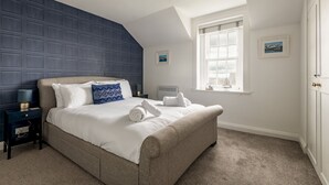 Ein Schlafzimmer mit einem großen Bett, einem Nachttisch, einem Fenster und einer Tür.