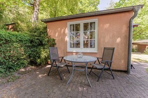 Ein kleines Gebäude mit einem Fenster und zwei Stühlen davor.