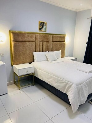 Ein Schlafzimmer mit Bett, Nachttischen, einer Nachttischlampe und einer Wandleuchte.