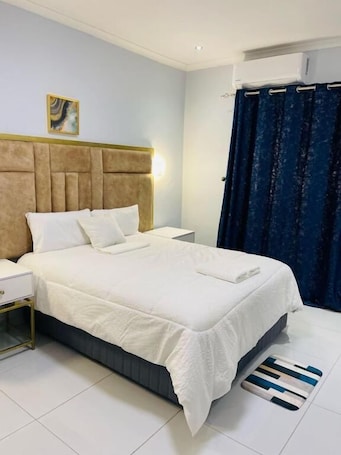 A hotel room with a bed, nightstand, and a wall-mounted air conditioner.. Paradise Reho Guesthouse