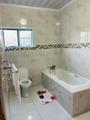 Ein Badezimmer mit Toilette, Badewanne und gefliesten Wänden.