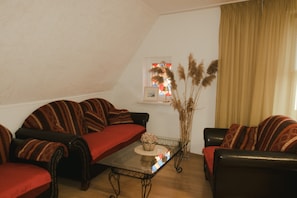 Ein gemütliches Wohnzimmer mit einer Sofagarnitur, einem Couchtisch und einer Vase mit Pampasgras.