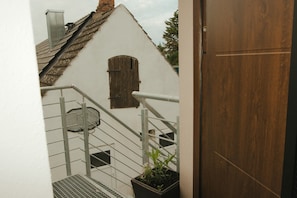 Ein weißes Gebäude mit Holztür, Metalltreppe und einem Blumentopf.