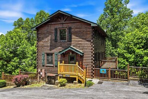 A log cabin with a porch, a staircase, and a sign indicating a restaurant. - New Listing | 5BR Gatlinburg Cabin w/ Hot Tub + Game Room + Free Tickets (Gatlinburg)