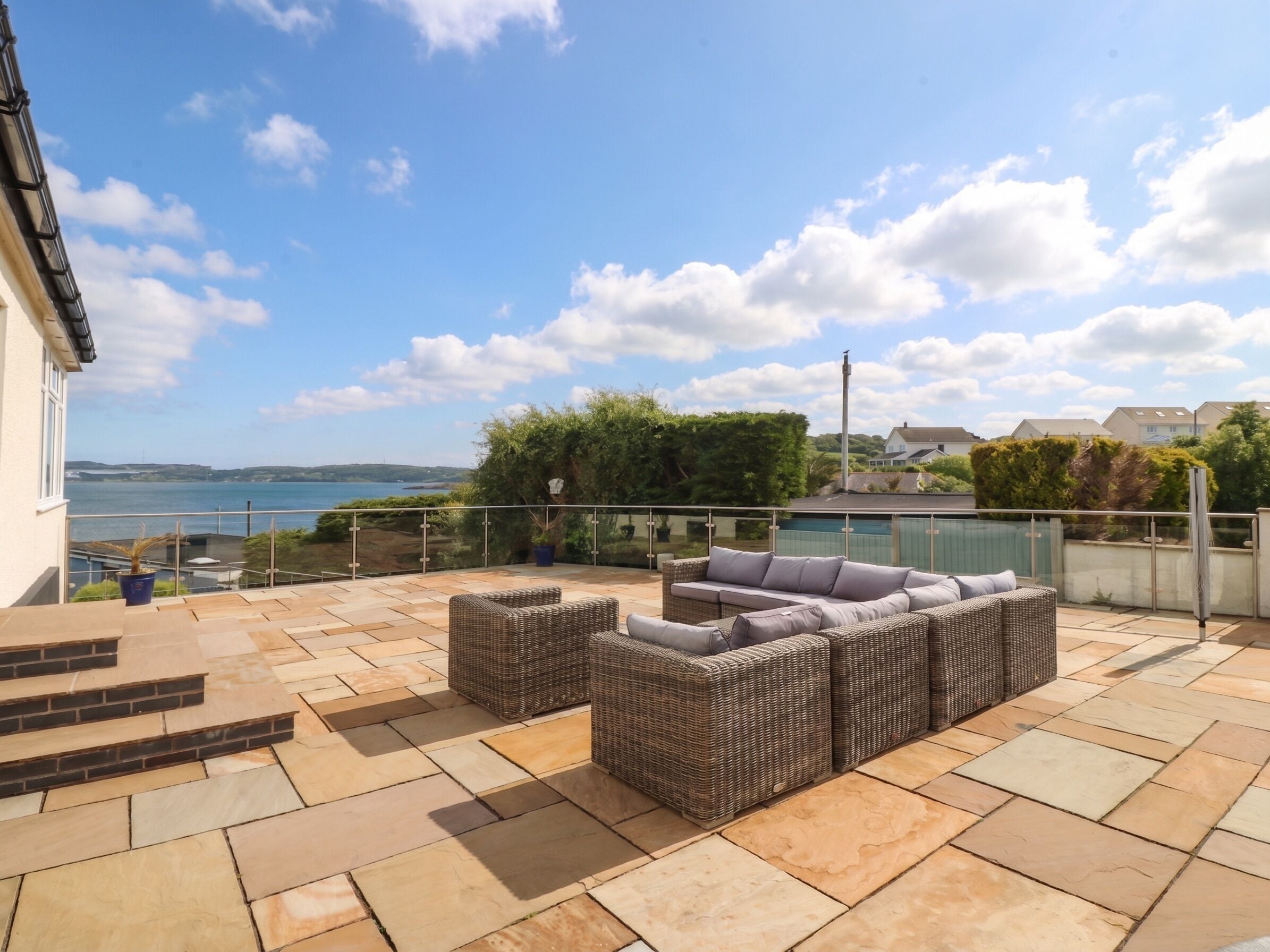 A patio with outdoor furniture and a view of the sea.