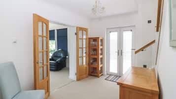 Una habitación con un escritorio de madera, una silla azul, un sillón de cuero y un aparador de vidrio.